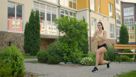 Training-of-the-legs-and-hips-in-the-city-park.-Young-woman-makes-lunges-in-city-park-on-walkway